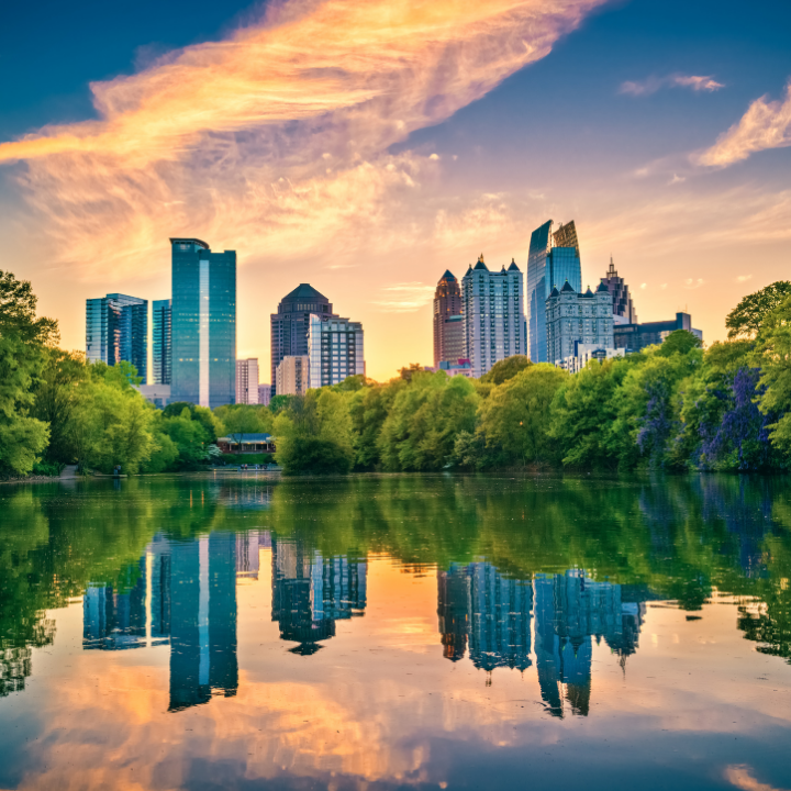 Modern skyscrapers of the Atlanta Perimeter skyline reflecting in a serene lake at sunset, framed by green trees—capturing the heart of temp staffing and consulting in Perimeter.