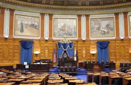 A government chamber with desks and flags, representing support for state and local programs.