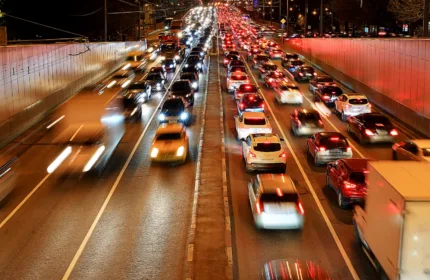 Cars an trucks on a straight, busy six lane highway at night